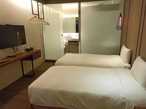 a hotel room with two beds and a flat screen tv at O2 Hotel Taipei Main Station in Taipei