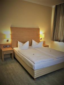 a bedroom with a large white bed with two tables at Pension Am Pollingpark in Dessau