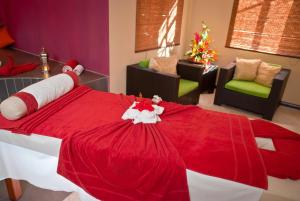 a red and white bed in a room with chairs at Jalsa Beach Hotel & Spa in Poste Lafayette