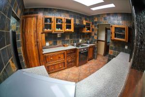 a kitchen with wooden cabinets and a tile wall at The Sweetest Spot in St Lucia