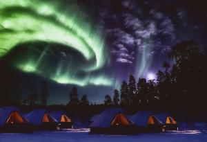 a group of tents under the aurora in the sky at Northern Lights Village Levi in Levi