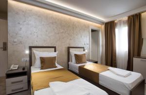 波德戈里察Hotel Fobra的有两张床和一张书桌的酒店房间