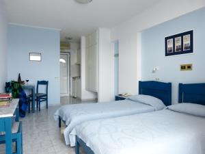 a bedroom with two beds and a table and chairs at Ostria Seaside Studios and Apartments in Katarráktis