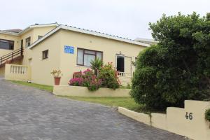 a white house with flowers in front of it at À La Mer - Selfcatering Unit in Agulhas