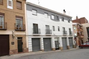 a white building on a street with a red car parked in front at ApartamentosAlquilerZaragoza in Zaragoza