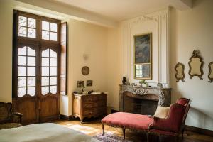 a bedroom with a fireplace and a bed and a chair at Château d’Orion in Orion
