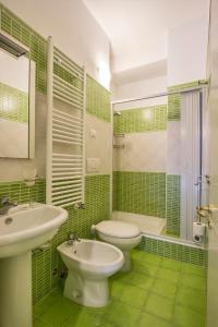 Baño de azulejos verdes con lavabo y aseo en Mamma Sisi, en Lecce