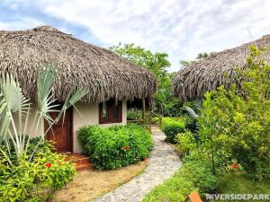 a small house with a thatch roof and a pathway at Riverside Park Eco Resort in Vĩnh Long