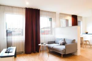 a living room with a couch and some windows at SEEGER Living Premium Downtown in Karlsruhe