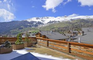 a house with a wooden fence and a mountain at Centre Etoile 130 in Verbier