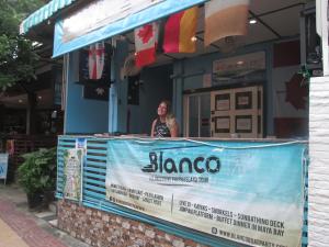 a woman standing behind a sign in front of a restaurant at Rehab Hostel in Phi Phi Don