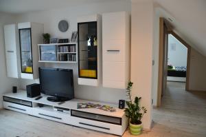 una sala de estar con TV en un centro de entretenimiento blanco en Ana`s place en Celje
