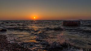 una puesta de sol sobre el océano con un muñón en el agua en Parkhotel del Mar en Sassnitz