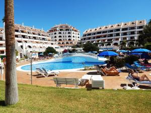 a resort with a swimming pool with people sitting in chairs at Beautiful Beachfront in Playa de las Americas