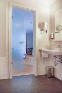 uma casa de banho com um lavatório, um espelho e uma porta em SEEGER Living Premium West em Karlsruhe