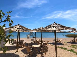 un gruppo di tavoli e sedie sotto ombrelloni su una spiaggia di Camping Vransko jezero - Crkvine a Pakoštane