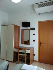 - une chambre avec un bureau, une armoire et un miroir dans l'établissement Hotel Clodia, à Chioggia