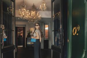 DOM Hotel Roma - Preferred Hotels & Resorts في روما: امرأة تقف في الردهة مع حقيبة زرقاء