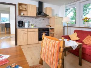 a living room with a red couch and a kitchen at Ferienwohnung Meierhof in Sankt Märgen