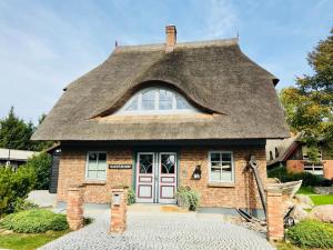 a small brick house with a thatched roof at "Kontorhaus" by Ferienhaus Strandgut in Born