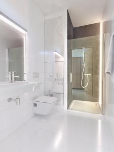 La salle de bains blanche est pourvue d'une douche et de toilettes. dans l'établissement Holiday Park & Resort Pobierowo, à Pobierowo