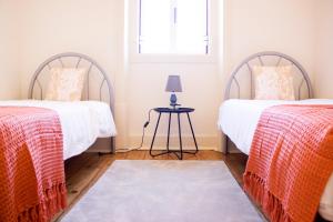 two beds in a room with a table and a window at Quintinha Vale dos Pinheiros in Leiria
