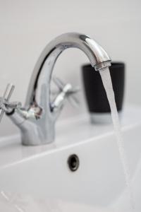 un évier de cuisine avec de l'eau qui coule d'un robinet dans l'établissement Kantrida Home, à Rijeka