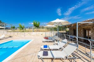 a pool with lounge chairs and an umbrella at Villa Evgoron in Zourídhion