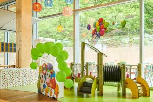 a nursery with green balloons and chairs and a staircase at Hotel Bellinzona Sud Swiss Quality in Monte Carasso
