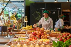 two people standing behind a buffet of food at Hotel Bellinzona Sud Swiss Quality in Monte Carasso