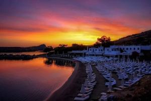 un grupo de sillas y sombrillas en la playa al atardecer en Lindos Vigli Private Villa en Lindos