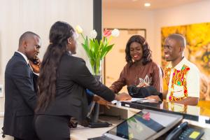 a group of people standing around a desk shaking hands at ONOMO Hotel Conakry in Conakry