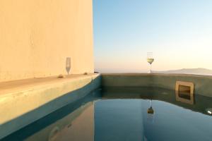 a glass of wine sitting on the edge of a swimming pool at Pearl on the Cliff Hotel & Suites by Pearl Hotel Collection in Imerovigli