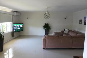 a living room with a couch and a tv at Edge Hill Clean & Green Cairns, 7 Minutes from the Airport, 7 Minutes to Cairns CBD & Reef Fleet Terminal in Cairns