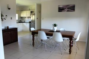 a kitchen and dining room with a wooden table and white chairs at Edge Hill Clean & Green Cairns, 7 Minutes from the Airport, 7 Minutes to Cairns CBD & Reef Fleet Terminal in Cairns