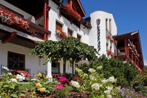 a building with a bunch of flowers in front of it at Hotel Brunnerhof in Rasùn di Sotto