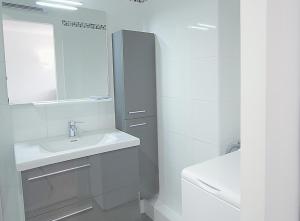 ein weißes Badezimmer mit einem Waschbecken und einem Spiegel in der Unterkunft Superbe T2 vue mer avec ascenseur in Canet-en-Roussillon