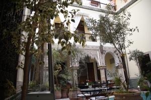 une cour d'un bâtiment avec des tables et des plantes en pot dans l'établissement Riad Al Loune, à Marrakech