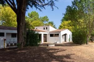 a white house with a tree in front of it at Camping Les Maraises in Saint-Martin-de-Ré