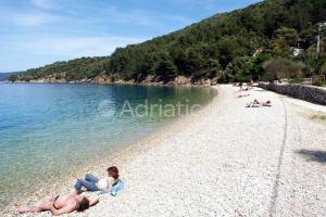 a group of people laying on a beach at Apartments and rooms Roberto B. in Valun