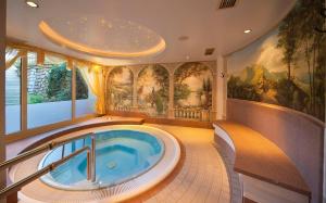 a jacuzzi tub in a room with paintings at Hotel Brunnerhof in Rasùn di Sotto