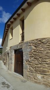 un edificio con una puerta de madera en su lateral en O Trancallo en Viana do Bolo