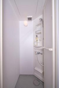 a small white bathroom with a shower in it at bnbplus Sarasa Nara in Nara