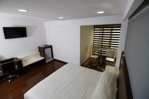 a bedroom with a bed and a desk and a television at Apart Hotel Regina in Cochabamba