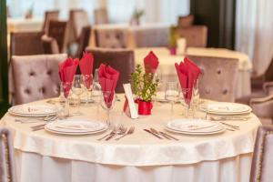 a white table with red napkins and glasses on it at Pensiunea Himalaya in Dărmăneasca