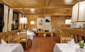 ein Restaurant mit weißen Tischen und Stühlen sowie Holzdecken in der Unterkunft Hotel Gersfelder Hof in Gersfeld