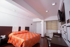 Schlafzimmer mit einem orangenen Bett und einem Schreibtisch in der Unterkunft Hotel Regina in Cochabamba