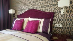 ブラックプールにあるThe Gatsby Blackpool - Formerly The Windsorのベッドルーム1室(紫と白の枕が備わるベッド1台付)