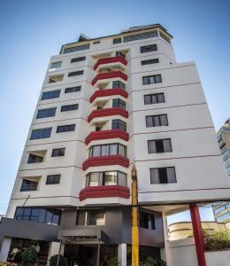 a tall white building with red windows at Apart Hotel Regina in Cochabamba