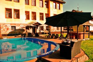 a pool with an umbrella next to a building at Penzion Adélka Janské Lázně in Janske Lazne